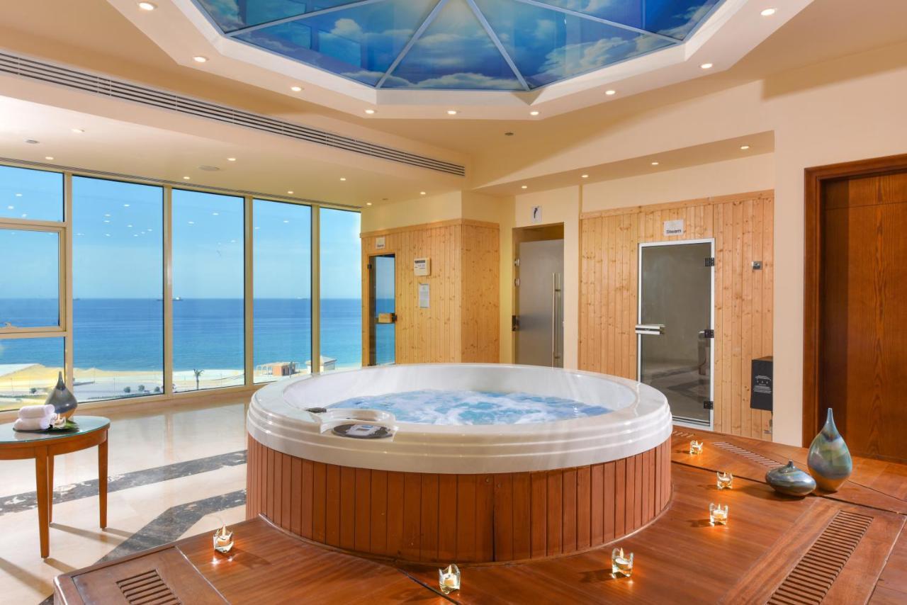 Tolip Resort El Galala Majestic Ain Sukhna Exterior foto The photo shows a luxurious spa room featuring a large, round hot tub positioned in the center. The walls are mostly glass, offering a stunning view of the ocean. The ceiling has a painted sky, enhancing the serene atmosphere. There are wooden elemen